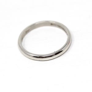 May include: A silver ring with a smooth, rounded band. The ring is set against a white background, highlighting its polished surface. The ring's design is simple and classic, suitable for everyday wear.