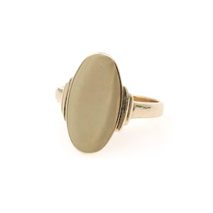 May include: A gold ring featuring a large, smooth, vertical oval-shaped face. The band connects to the central oval with tiered, stepped detailing on both sides. The metal has a polished, reflective finish throughout the entire piece.