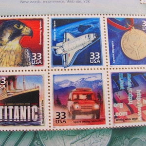 Puede incluir: Una hoja de nueve sellos postales con diferentes temas, incluyendo un halcón, un transbordador espacial, una medalla deportiva, un teclado de computadora, un automóvil y el Titanic. Cada sello tiene un borde azul y rojo y las palabras "33 USA" impresas en él.