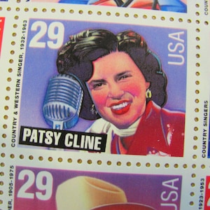 May include: A vintage US postage stamp featuring a portrait of Patsy Cline, a country and western singer, with a microphone. The stamp is blue and white with the text "COUNTRY & WESTERN SINGER, 1932-1963" and "PATSY CLINE" printed on it.
