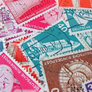 May include: A collection of vintage German postage stamps featuring various designs, including a building, an airplane, and a tower. The stamps are in different colors, including red, blue, green, and brown. The stamps have the text "Deutsche Bundespost" and "Deutsche" printed on them.