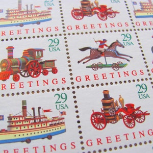 Puede incluir: Una hoja de sellos postales estadounidenses vintage de 29 centavos que presentan una variedad de diseños de juguetes, incluyendo un tren de juguete, un caballo de juguete y un jinete, un camión de bomberos de juguete y un barco de vapor de juguete. Los sellos están impresos en papel blanco con acentos rojos y verdes. El texto "Greetings" está impreso en cada sello.