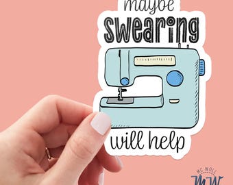 May include: A sticker with a light blue sewing machine illustration and the text "maybe swearing will help" in black. The sticker is held against a pink background.