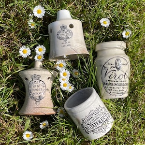 May include: A collection of four vintage ceramic kitchen items including two bell-shaped pie funnels with The Gourmet Pie Cup branding, a Virol bone-marrow jar, and a J. Sainsbury's Bloater Paste pot, all featuring black printed text and logos.
