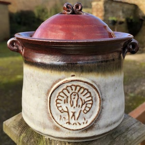 May include: A white ceramic jar with a brown and red lid. The jar has a brown and white design and a circular image of a turkey on the front.