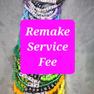 Op de afbeelding: Een close-up van een stapel kleurrijke kralenarmbanden met woorden zoals "Make it Happen", "Dream Big", "Hustle", "Happiness" en "FOMO". De tekst "Remake Service Fee" is geschreven in witte letters op een felroze achtergrond.