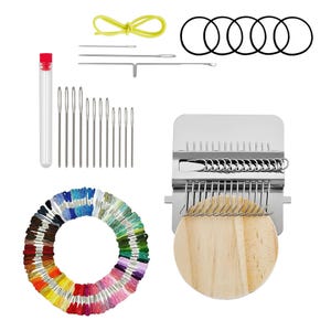 Może przedstawiać: Zestaw rzemieślniczy z różnymi narzędziami do tkania i haftowania. Zawiera krosno z drewnianą podstawą, igły, tubę igieł, tęczę nici do haftu, gumki recepturki i żółty sznurek.