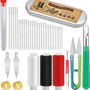 Op de afbeelding: Een naaikit met diverse gereedschappen en accessoires. Bevat een metalen doos met het opschrift "SEWING NEEDLES KIT", naalden, spoelen met wit, zwart en rood garen, een schaar, een tornmesje, vingerhoeden en inrijgers.