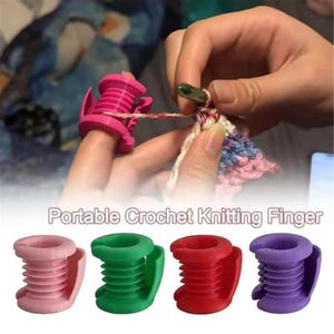 May include: A set of four plastic yarn tension guides in light pink, green, red, and purple. Each ring features a ribbed cylindrical design with a side slot for yarn. The text Portable Crochet Knitting Finger is printed below the items.