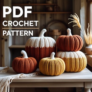 Könnte beinhalten: Eine Ansammlung gehäkelter Kürbisse in verschiedenen Größen und Farben, darunter Orange, Gelb und Creme. Die Kürbisse sind auf einem Holztisch angeordnet. Der Text "PDF CROCHET PATTERN" ist ebenfalls zu sehen.