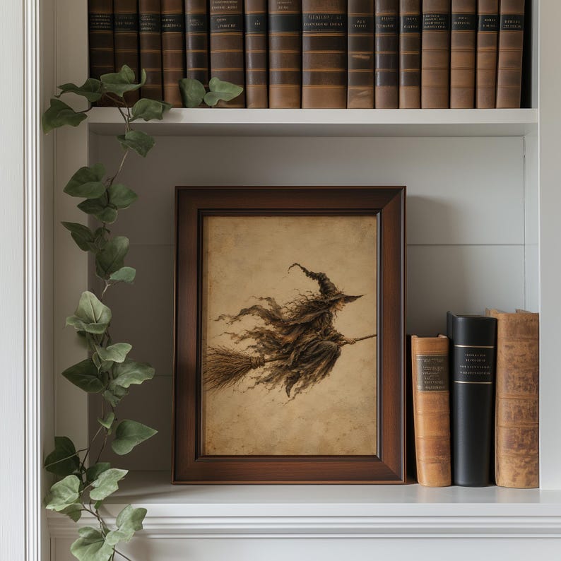 May include: A framed rectangular wall art print featuring a sepia-toned illustration of a witch wearing a pointed hat and tattered robes while flying on a broomstick. The artwork is displayed in a dark brown wooden frame with a simple border.