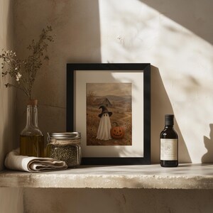 Cottagecore Halloween painting wall art featuring ghostly figure in witch hat among dried grasses and weathered structures