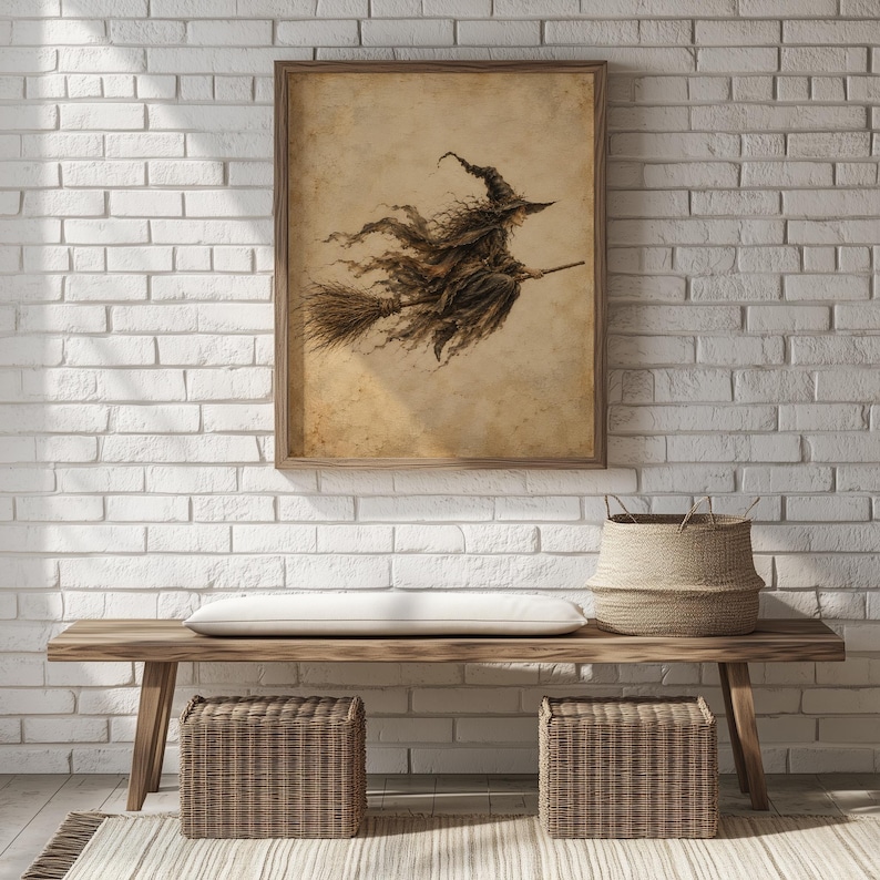 May include: A framed wall art print featuring a sepia-toned illustration of a witch flying on a broomstick. The artwork is displayed on a white brick wall above a wooden bench with a white cushion and two woven wicker storage baskets underneath.
