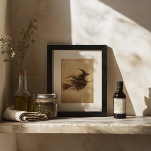 May include: A framed art print featuring a dark, sepia-toned illustration of a witch flying on a broomstick. The print is displayed in a black frame alongside a clear glass bottle of oil, a glass jar filled with dried herbs, and a small dark bottle.