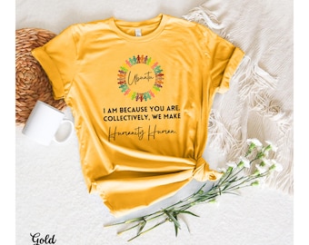 May include: A gold-colored t-shirt with the word "Ubuntu" and a graphic of people holding hands. The shirt also features the text "I am because you are. Collectively, we make Humanity Human."