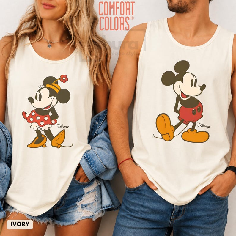 Puede incluir: Dos camisetas sin mangas de color marfil con gr&aacute;ficos de personajes de Disney. La camiseta de la izquierda muestra a Minnie Mouse con una falda de lunares rojos y zapatos amarillos. La de la derecha muestra a Mickey Mouse con pantalones cortos rojos y zapatos amarillos. Incluyen el logo de Disney.