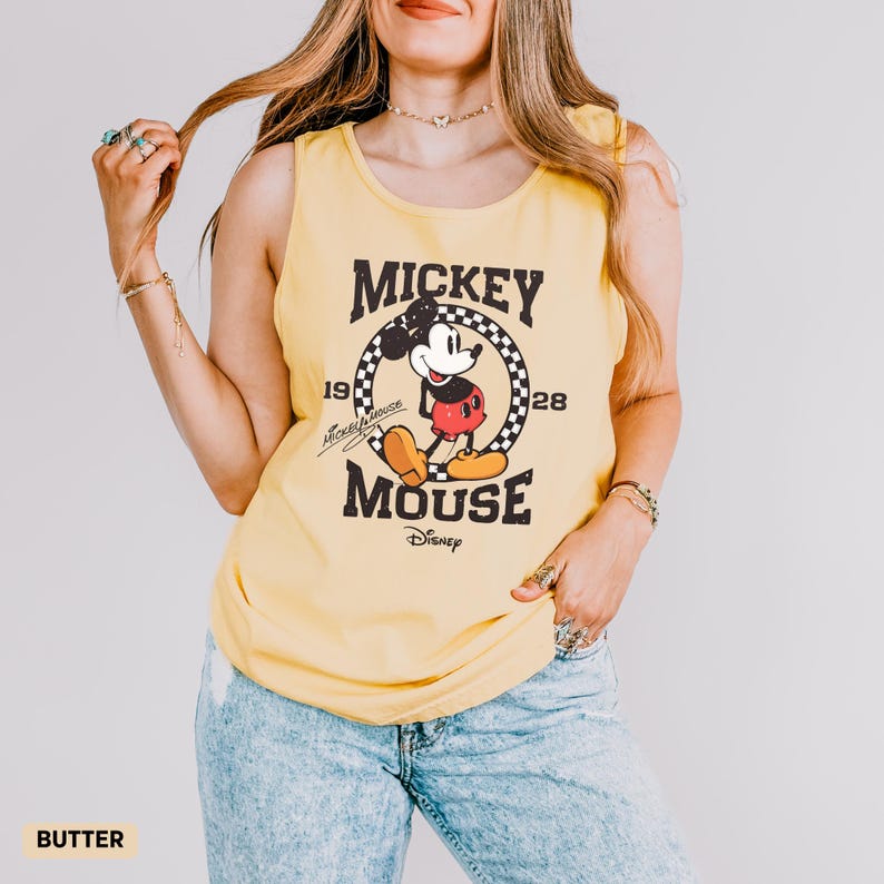 K&ouml;nnte beinhalten: Gelbes Tanktop mit Mickey Mouse-Grafik. Die Grafik enth&auml;lt die W&ouml;rter "Mickey Mouse" und "1928" mit einem Bild von Mickey Mouse. Das Tanktop hat eine einfarbige gelbe Farbe.