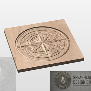 May include: A wooden square featuring a detailed compass rose design. The compass rose is carved into the wood, with directional markers and a central star design. The image also includes the Spearhead Design Company logo.