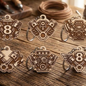 May include: A collection of six wooden keychains with engine designs. The keychains are laser-cut with intricate details, including pistons, wings, and the number 8. They are displayed on a wooden surface.