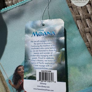Puede incluir: Una bolsa con cremallera de color turquesa con un dise&ntilde;o de Disney Moana. La bolsa tiene una etiqueta con texto sobre la pel&iacute;cula y un c&oacute;digo de barras. El fondo es una textura tejida. La bolsa es probablemente de tela.