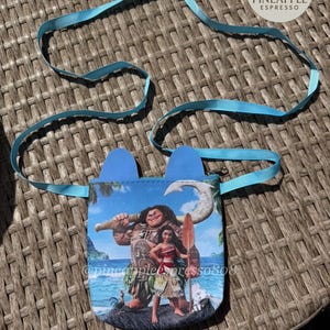 Puede incluir: Una peque&ntilde;a bolsa azul con una correa azul claro, con un gr&aacute;fico colorido de personajes de una popular pel&iacute;cula de animaci&oacute;n. La bolsa tiene dos acentos azules en forma de oreja en la parte superior. El texto "@pineapplepress808" es visible.