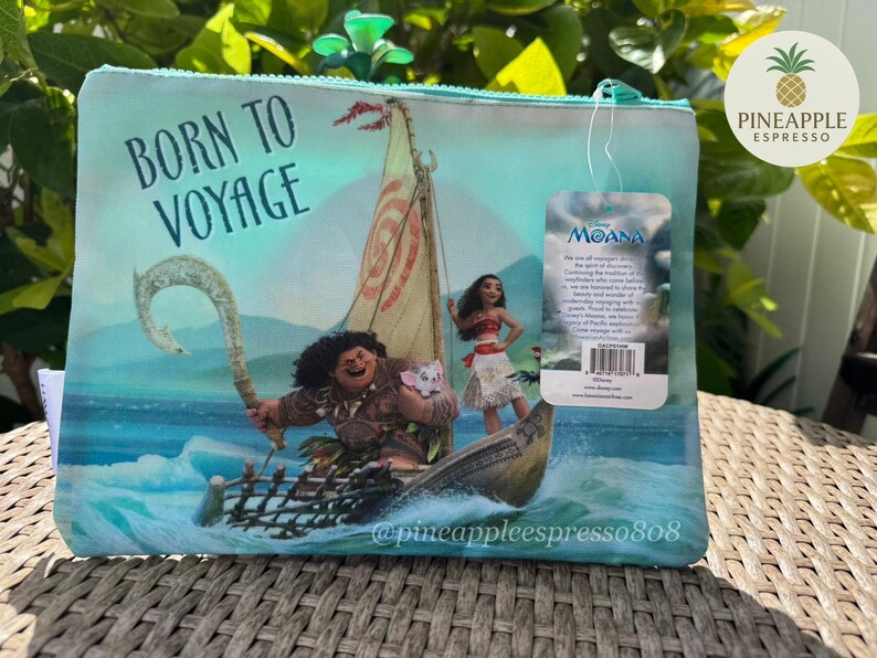 Puede incluir: Una bolsa con cremallera azul claro con una escena de la pel&iacute;cula de Disney Moana. La imagen muestra a Moana, Maui y un barco en el oc&eacute;ano, con el texto "BORN TO VOYAGE". Una etiqueta con el logotipo de Moana est&aacute; adjunta.