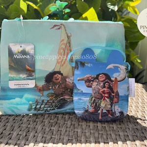 Puede incluir: Dos bolsas con tem&aacute;tica de Moana con un dise&ntilde;o tropical. Una es una bolsa rectangular azul claro con cremallera, y la otra es una bolsa redonda azul con asa. Ambas presentan personajes de la pel&iacute;cula.