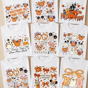 May include: Nine white t-shirts featuring various Halloween-themed graphics in orange, black, and purple. Designs include pumpkins, mouse ears, ghosts, spider webs, and text such as Nightmare on Main Street, Halloween, and Trick or Treat.