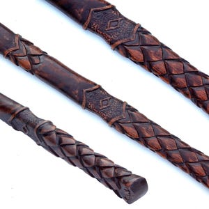 May include: Three dark brown, carved wooden handles with intricate woven and geometric patterns. The handles are displayed at different angles, showcasing the detailed craftsmanship and texture of the wood.
