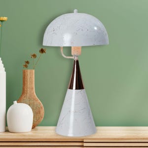 May include: A white and copper-toned table lamp with a marble-like pattern. The lamp features a dome-shaped shade and a conical base. The lamp is a decorative lighting fixture.
