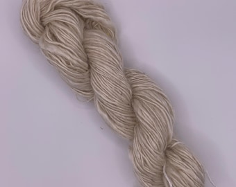 Può includere: Un gomitolo di filato color crema, ben attorcigliato. Il filato ha un aspetto morbido e naturale con una superficie leggermente strutturata. Le fibre sono ben filate, suggerendo durata. Ideale per lavorare a maglia, all'uncinetto o altri progetti di arte tessile.