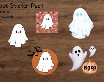 May include: A selection of Halloween ghost stickers. The stickers feature white ghost designs in various shapes, some with friendly faces, and a pumpkin with "BOO!" text. The background is a wooden surface.