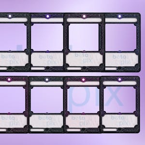 以下が含まれることがあります： 装飾的な黒い縁と白い内側を備えた8つの装飾的なカードフレーム。各フレームには長方形の開口部があり、上部に小さな円形のライトがあります。「beta pix」というテキストが各フレームに表示されます。