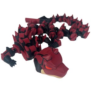 May include: A red and black articulated dragon toy with a detailed design. The dragon has a segmented body, sharp spikes, and a detailed head with red eyes. The toy is made of plastic and appears to be 3D-printed.