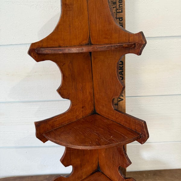 Un estante esquinero de madera vintage de tres niveles.