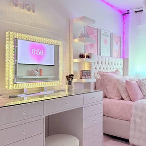 Peut inclure: Chambre luxueuse avec une coiffeuse blanche, un lit avec une literie rose et un grand miroir avec un cadre en cristal. La pièce est décorée dans des tons roses et blancs, avec un tapis moelleux et des étagères décoratives.