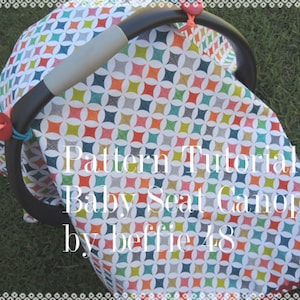 Può includere: Una cappottina per seggiolino auto colorata con un motivo geometrico in tonalità di blu, verde, rosso, arancione e giallo. La cappottina è realizzata in tessuto e ha uno sfondo bianco. Il testo "Pattern Tutorial Baby Seat Canopy by beffie48" è stampato sulla cappottina.