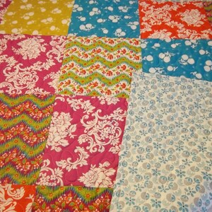 May include: A patchwork quilt with a variety of colorful patterns, including floral, geometric, and paisley designs. The quilt is made from different fabrics in shades of pink, blue, green, yellow, and orange.
