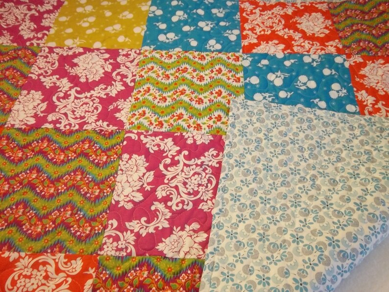 May include: A patchwork quilt with a variety of colorful patterns, including floral, geometric, and paisley designs. The quilt is made from different fabrics in shades of pink, blue, green, yellow, and orange.