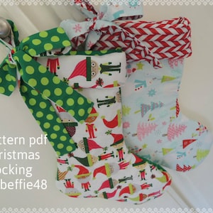 May include: Three Christmas stockings with different patterns. The stocking on the left has a green polka dot ribbon and a white background with a repeating pattern of elves. The stocking in the middle has a red and white striped pattern. The stocking on the right has a light blue background with a repeating pattern of Christmas trees. The text "Pattern pdf Christmas Stocking by beffie48" is visible at the bottom of the image.