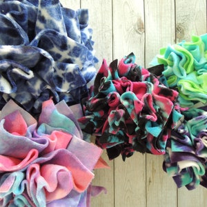 May include: Five handmade dog toys made from colourful fleece fabric. The toys are in the shape of balls and are tied together with a ribbon.
