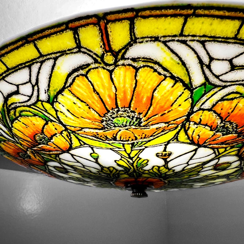 May include: A stained glass ceiling light fixture featuring a floral design with orange and yellow flowers, green leaves, and white accents. The fixture has a black metal base and is mounted on a white ceiling.