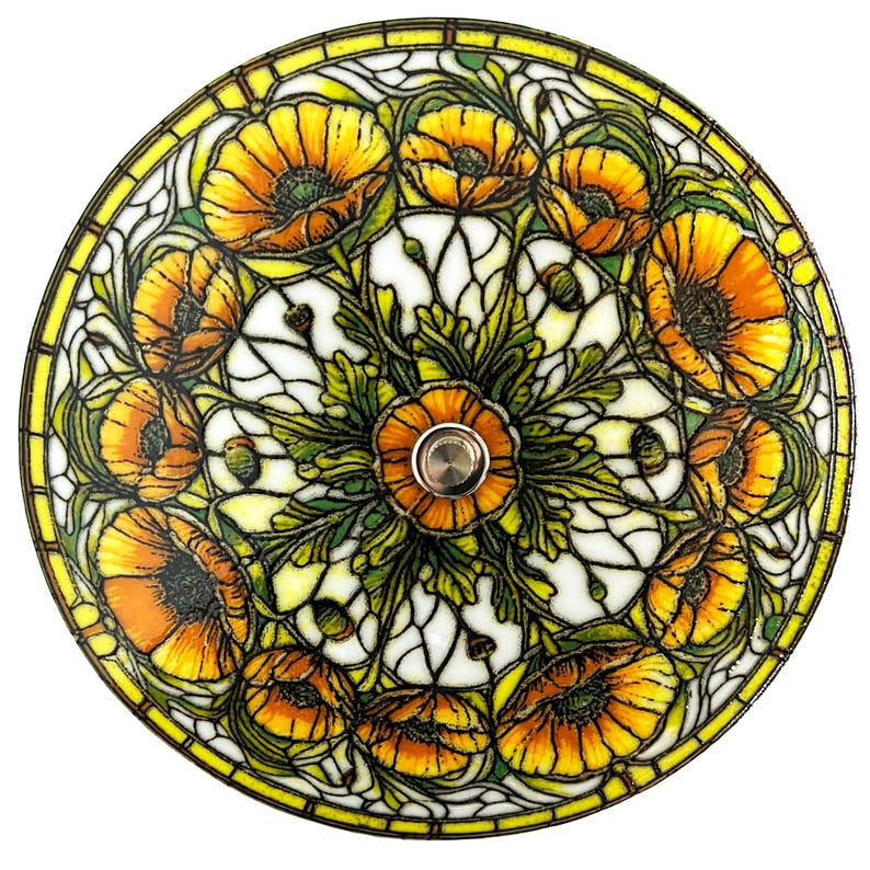 May include: A stained glass lamp shade featuring a floral design with orange and yellow poppies, green leaves, and white background. The shade has a yellow border and a silver center fixture.