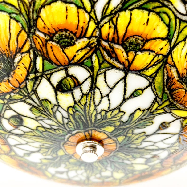 May include: Close-up of a stained glass lamp shade featuring a floral design. The shade has a pattern of yellow and orange poppies, white flowers, and green leaves. The lamp has a metal fixture in the center.