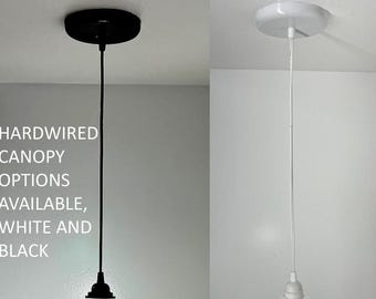 May include: Two pendant light fixtures with hardwired canopy options. One has a black canopy and cord, the other has a white canopy and cord. The text in the image reads: HARDWIRED CANOPY OPTIONS AVAILABLE, WHITE AND BLACK.