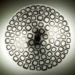 May include: A white ceiling light fixture with a black geometric pattern of squares and rectangles.