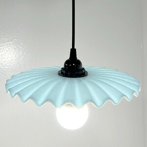 May include: A light blue glass pendant light with a scalloped edge and a black cord.