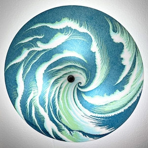 May include: A round, blue and white ceiling light fixture with a swirling pattern. The light fixture has a small black center.