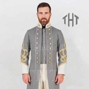 Könnte beinhalten: Ein grauer Mantel im Militärstil mit goldenen Details und Knöpfen. Der Mantel hat weiße Manschetten und goldene Stickereien auf den Ärmeln. Der Kragen hat goldene Details. Der Mantel ist Teil eines formellen Outfits.