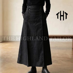 Może przedstawiać: Długa, czarna spódnica z wysoką talią i detalami w postaci guzików. Spódnica ma rozkloszowaną sylwetkę i kieszenie. Tekst "THE HIGHLAND TAILOR" jest wydrukowany na dole obrazu.